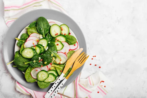 salad with sliced radish and cucumber with wooden fork and knife