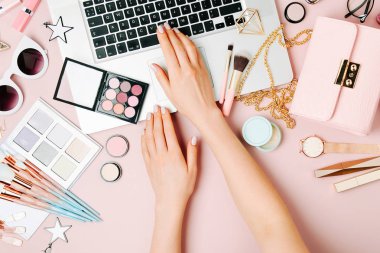 Moda blogger laptop ile çalışma. Kadın Aksesuar, kozmetik ürünleri soluk pembe tablo ile çalışma alanı. düz yatıyordu, en iyi görünümü
