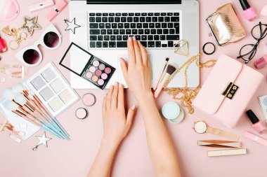 Moda blogger laptop ile çalışma. Kadın Aksesuar, kozmetik ürünleri soluk pembe tablo ile çalışma alanı. düz yatıyordu, en iyi görünümü