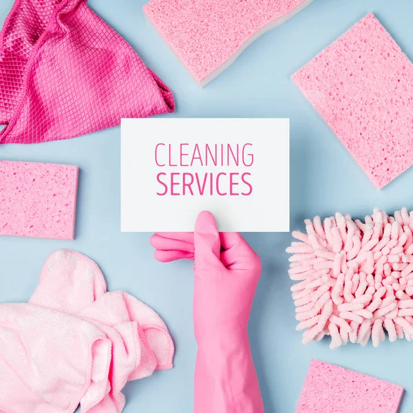 Hands in pink gloves hold empty card. Cleaning or housekeeping concept background. Copy space. Flat lay, Top view.