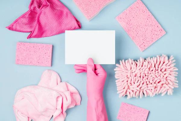 Hand in pink gloves hold empty card. Cleaning or housekeeping concept background. Copy space. Flat lay, Top view.