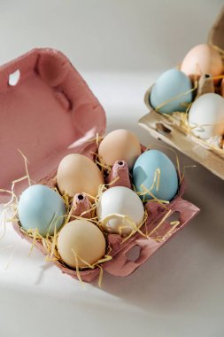 Doğal renkli kahverengi ve beyaz yumurta yumurta kutusunda sunlights ile... Besteleri pastel renklerde. Paskalya consept.  