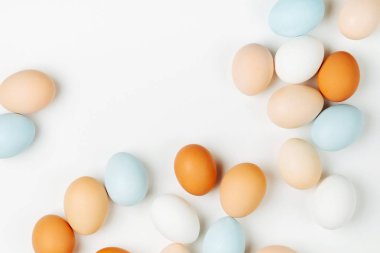 Doğal renkli kahverengi ve beyaz yumurta ışık arka plan üzerinde. Besteleri pastel renklerde. Paskalya consept. Düz yatıyordu, en iyi görünümü 