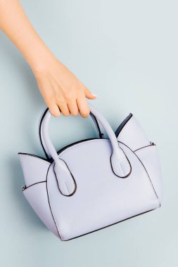 Eller el çantası mavi arka plan üzerinde tutar. Düz yatıyordu, en iyi görünüm. Pastel renkli moda kavramı bahar