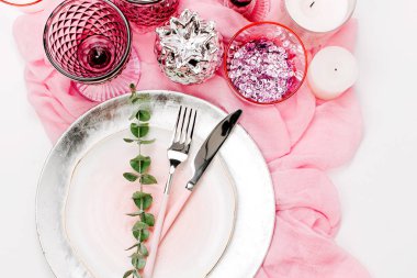 Sofra pastel pembe ve beyaz renklerle, vintage kadehler, yeşil yaprakları beyaz arka plan üzerinde izole bileşimi