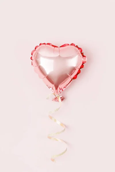 Single Balloon of heart shaped foil on pastel pink background. Love concept. Holiday celebration. Valentine\'s Day or wedding/bachelorette party decoration. Metallic balloon