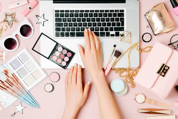 Moda blogger laptop ile çalışma. Kadın Aksesuar, kozmetik ürünleri soluk pembe tablo ile çalışma alanı. düz yatıyordu, en iyi görünümü