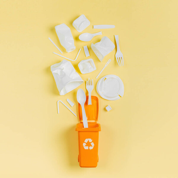 White single use plastic in garbage bin on  yellow background