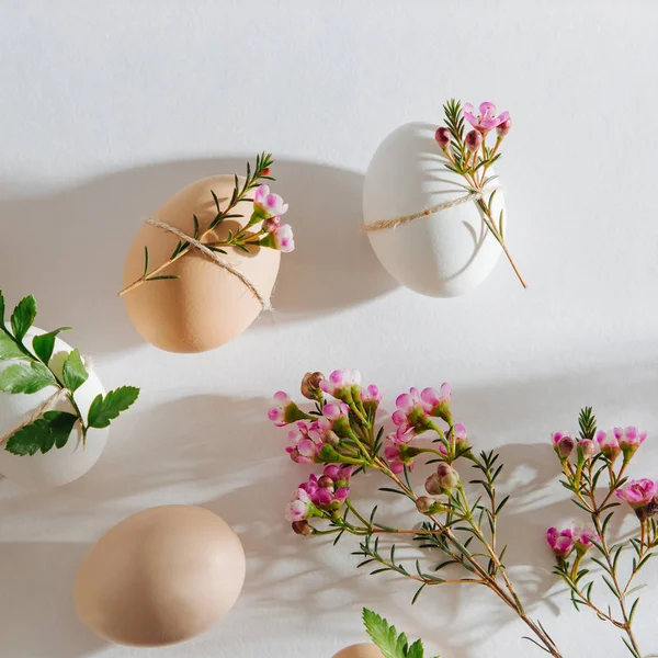 Natural Colored Eggs decorated with flowers in morning sunlights. Stylish minimal Compositions in pastel colors.  Easter concept.