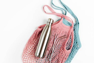 Beyaz arka plan üzerinde yeniden kullanılabilir metal su şişesi ile çanta örgü. Sürdürülebilir bir yaşam tarzı. Sıfır atık kavramı. Hiçbir plastik.