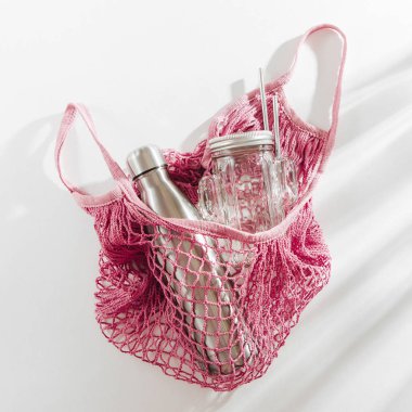 Yeniden kullanılabilir metal su şişe, cam kavanoz ve saman ile pamuk net çanta. Sıfır atık kavramı. Çevre Dostu