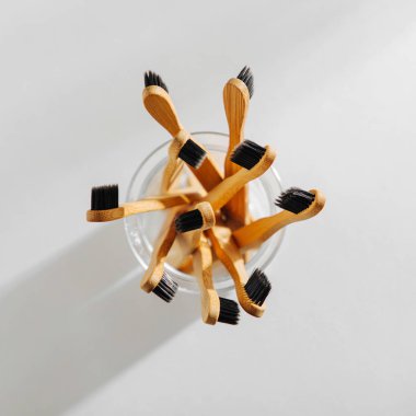 Ahşap Eko bambu diş fırçası ile cam beyaz arka planda siyah kıl. Sürdürülebilir bir yaşam tarzı. Sıfır atık kavramı.