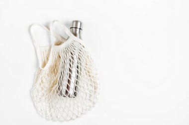 Beyaz arka plan üzerinde yeniden kullanılabilir metal su şişesi ile çanta örgü. Sürdürülebilir bir yaşam tarzı. Sıfır atık kavramı. Hiçbir plastik.