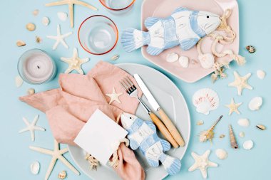 Sofra ve deniz süslemeleri şenlikli bir tablo hizmet için. Tabaklar, şarap, gözlük ve çatal bıçak takımı mavi zemin üzerine. Yaz konsepti. Düz yatıyordu, en iyi görünümü