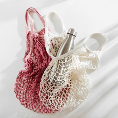 Beyaz arka plan üzerinde yeniden kullanılabilir metal su şişesi ile çanta örgü. Sürdürülebilir bir yaşam tarzı. Sıfır atık kavramı. Hiçbir plastik.