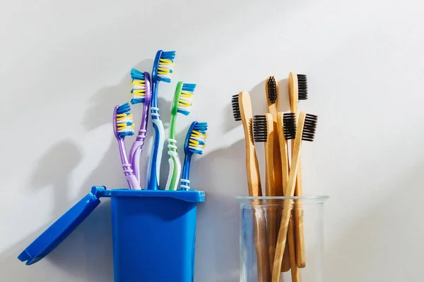 Eco friendly bamboo toothbrushes in glass and plastic toothbrushes in trash bin. Zero waste, plastic free, ecology concept.