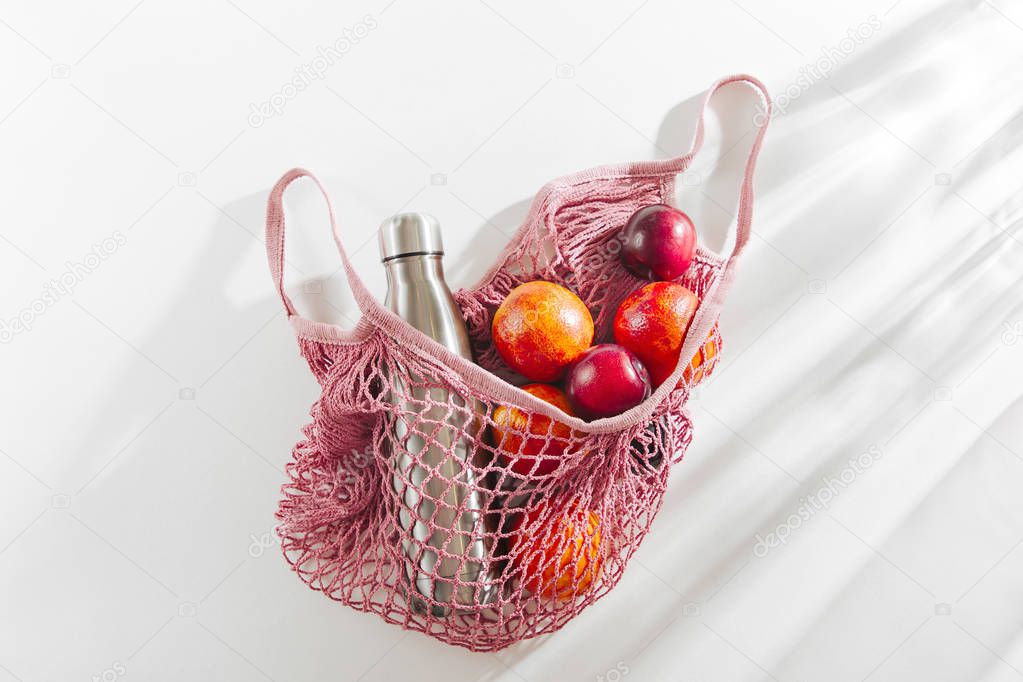 Cotton net bag with reusable metal water bottle and fruits. Sustainable lifestyle.  Eco friendly concept.