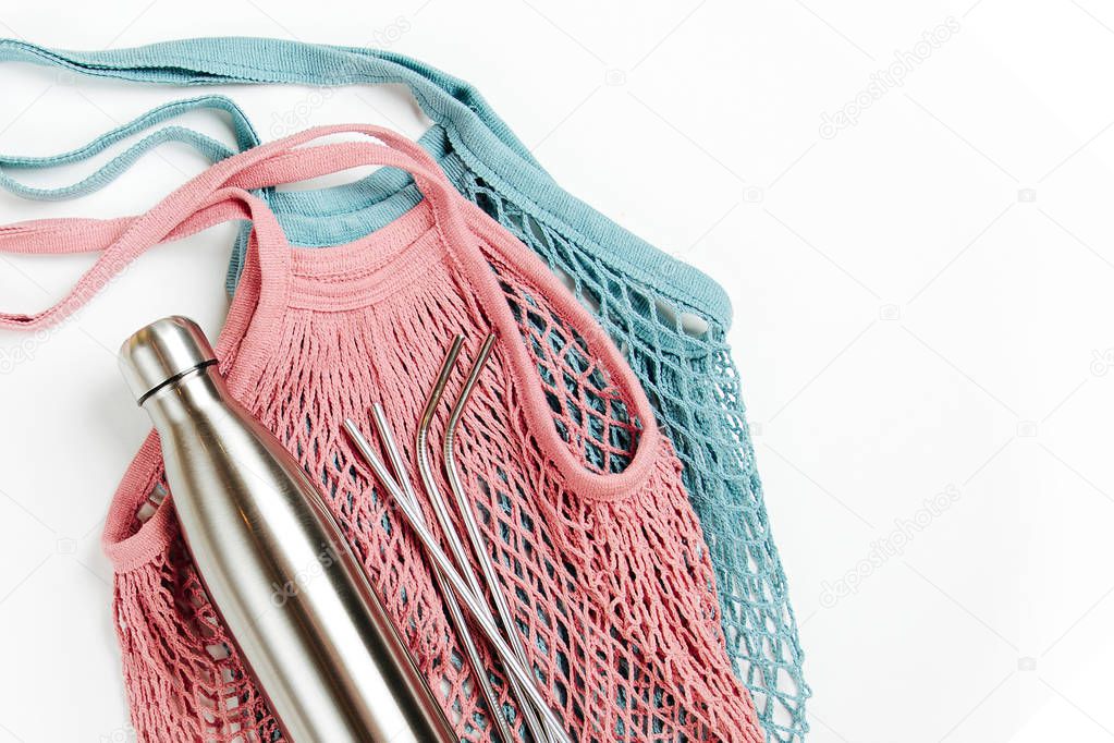 Mesh bags with reusable metal water bottle on white background. Sustainable lifestyle. Zero waste concept. No plastic.