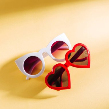 Sarı arka plan üzerinde parlak güneş ışığı ile Şık güneş gözlüğü seti. Düz yatıyordu, üstten bak. Yaz moda konsepti