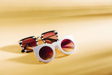 Sarı arka plan üzerinde parlak güneş ışığı ile Şık güneş gözlüğü seti. Düz yatıyordu, üstten bak. Yaz moda konsepti