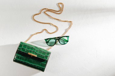 Beyaz arka planda güneş gözlüğü ile Moda yeşil çanta. Düz yatıyordu, üstten bak. Yaz moda konsepti