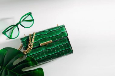 Çanta, güneş gözlüğü ve tropikal yaprak ile kadınsı aksesuarları kolaj. Düz yatıyordu, üstten bak. Yaz moda konsepti