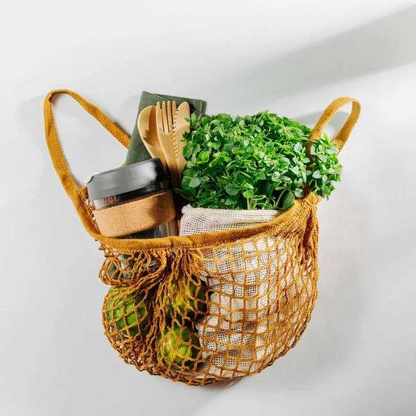 Eco bag with Eco friendly bamboo cutlery, reusable coffee mug and fresh green. Sustainable lifestyle. Plastic free concept. Flat lay, top view