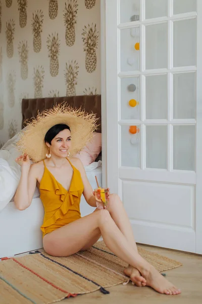 Young Woman Yellow Swimsuit Straw Hat Cocktail Sits Bed Hotel — 스톡 사진
