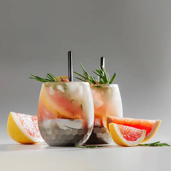 グレープフルーツとローズマリーカクテルの2つのガラス 新鮮な柑橘類と氷で夏のドリンク — ストック写真