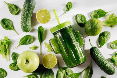 Ispanaklı, yeşil meyveli ve sebzeli kaktüs şeklinde şirin cam kavanoz şeklinde yeşil smoothie beyaz masada. Vejetaryen yemeği. Detoks ve diyet kavramı. 