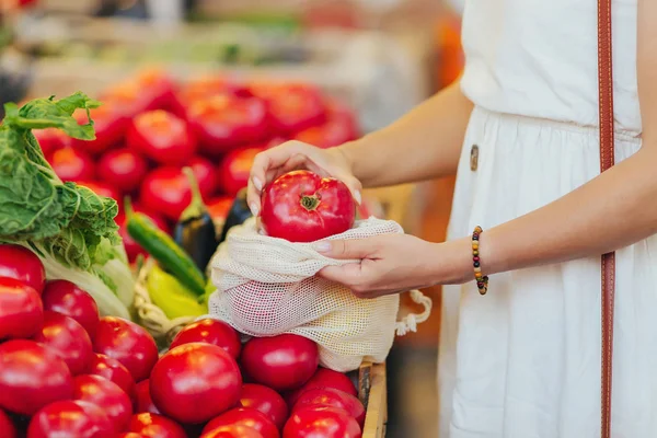 女性の手は 食品市場で綿の生産袋に果物や野菜を置きます 買い物に再利用可能なエコバッグ 廃棄物ゼロの概念 — ストック写真