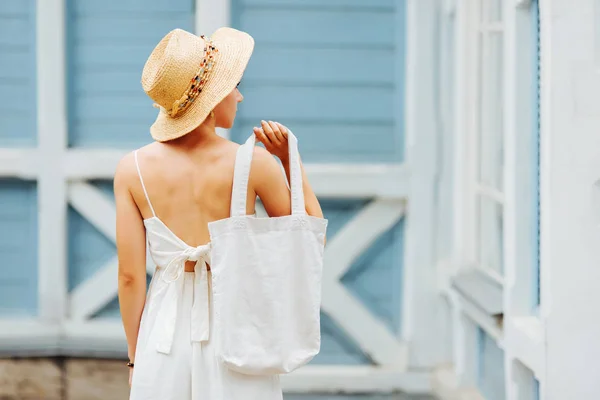 Woman with cotton bag near blue wall. Mockup for design. Reusable eco bag for shopping. Zero waste concept.