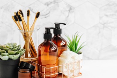 Banyo aksesuarları, doğal kozmetik ürünleri ve araçları ile beyaz masa üzerinde yeşil bitki 