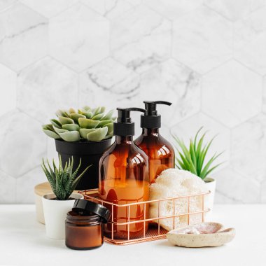 Banyo aksesuarları, doğal kozmetik ürünleri ve araçları ile beyaz masa üzerinde yeşil bitki 