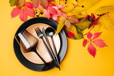 Turuncu arka planda parlak sonbahar yaprakları ile şenlikli masa ayarı