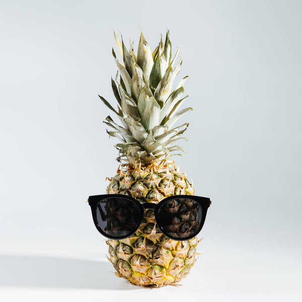 Pineapple in sunglasses on white background 
