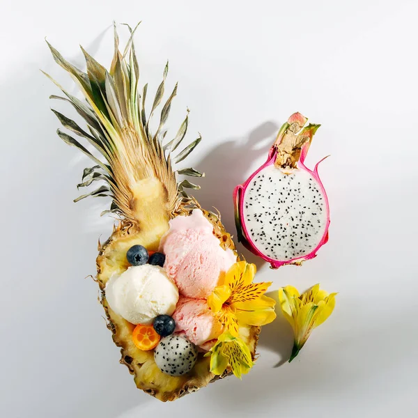 以花和浆果装饰的冰淇淋球 在菠萝的一半 — 图库照片