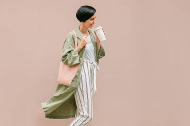 Kısa saçlı kadın yeniden kahve bardağı ve Eko Çanta sabah zevk tutarak. Çevre dostu konsept.