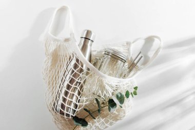 Yeniden kullanılabilir metal su şişesi, cam kavanoz ve saman ile pamuk net çanta