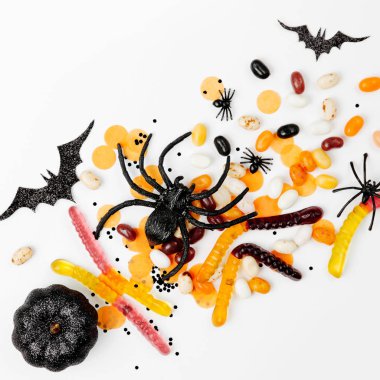 Cadılar Bayramı tatil süslemeleri, renkli şeker, yarasalar, beyaz arka planda örümcekler