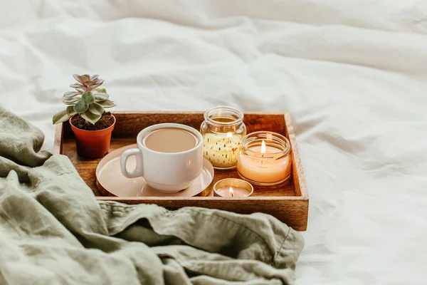 White bedding with dressing gown, tray of coffee and candles