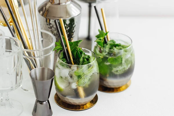 Cocktails with lime, mint and ice and bar accessories