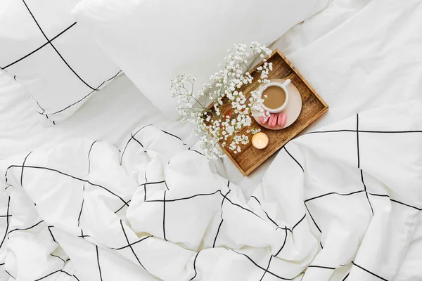 Wooden tray of coffee and candles with flowers on bed