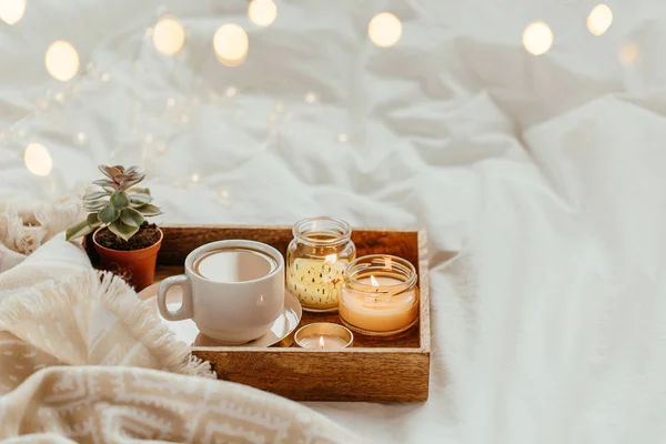 咖啡和蜡烛托盘 白色床上用品上带有暖格子 — 图库照片