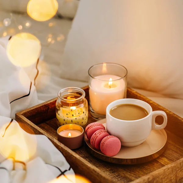 Wooden tray of coffee and candles on bed, hygge concept