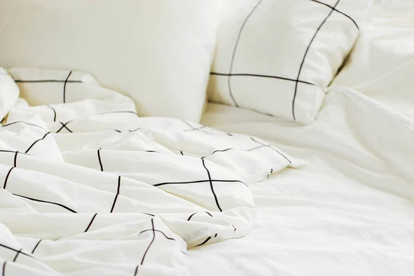 White bedding sheets with striped blanket and pillows