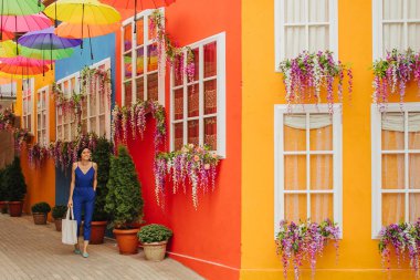 Mavi elbiseli kadın şehrin parlak dekorasyonu ile sokaklarda yürüyor. 