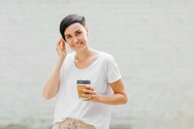 Genç bir kadın elinde yeniden kullanılabilir kahve bardağı tutuyor. Sürdürülebilir yaşam tarzı. Çevre dostu konsept.