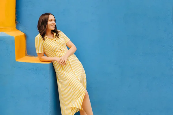 Şehirde Parlak Mavi Arka Plan Üzerinde Sarı Elbiseli Kadın — Stok fotoğraf