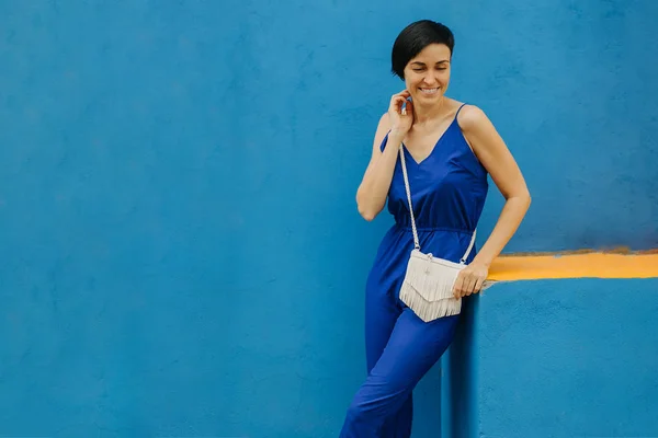Woman in blue clothes on bright blue background in the city.